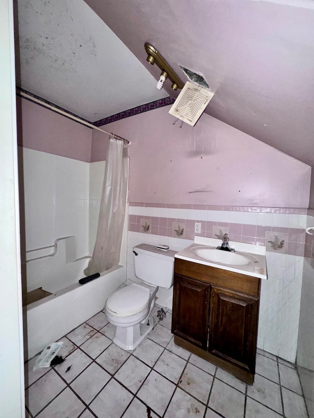 full bathroom with tile patterned flooring, toilet, shower / bath combo with shower curtain, vanity, and tile walls