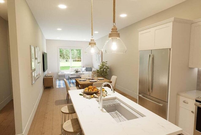 kitchen with stainless steel appliances, white cabinets, sink, and pendant lighting