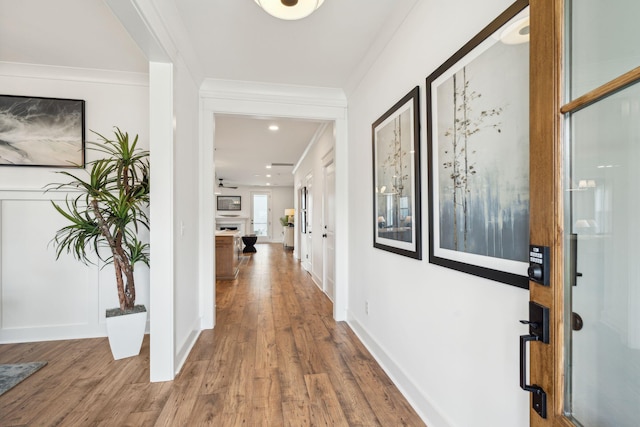 corridor with hardwood / wood-style flooring and ornamental molding