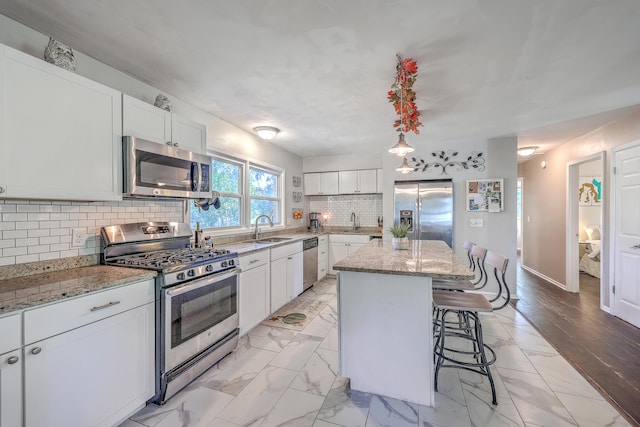 kitchen featuring white cabinets, decorative backsplash, light hardwood / wood-style floors, appliances with stainless steel finishes, and a kitchen island