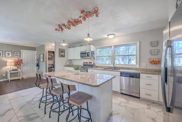 kitchen featuring white cabinets, appliances with stainless steel finishes, decorative light fixtures, and a kitchen island