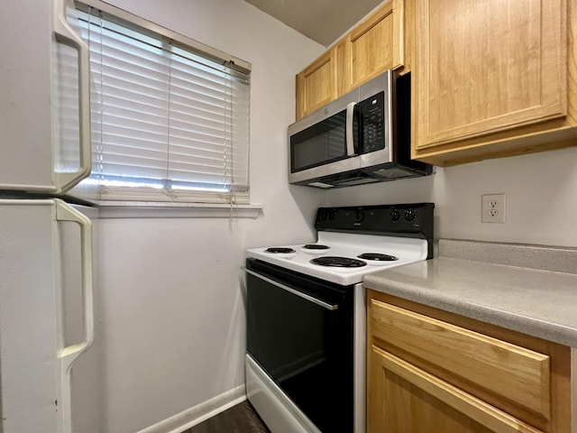 kitchen with light brown cabinets, white range with electric cooktop, and fridge