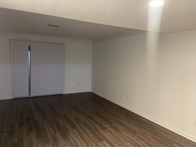 unfurnished room featuring dark wood-type flooring and a textured ceiling