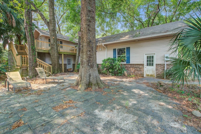 6094 Chisolm Rd, Johns Island, SC 29455 - view of front of property featuring stairway, a patio area, brick siding, and a wooden deck