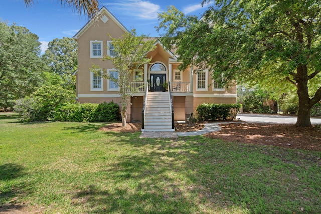 view of front facade with stairway, stucco siding, and a front lawn