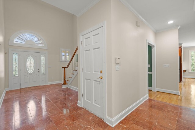 entryway with crown molding, baseboards, and stairway