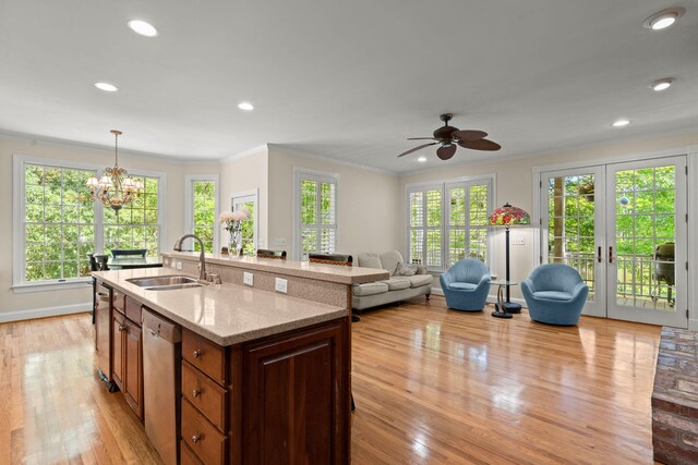 kitchen with a sink, stainless steel dishwasher, ornamental molding, light wood-style flooring, and light stone counters