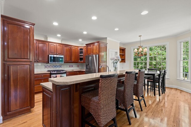 kitchen featuring stainless steel appliances, a breakfast bar, a chandelier, light countertops, and ornamental molding