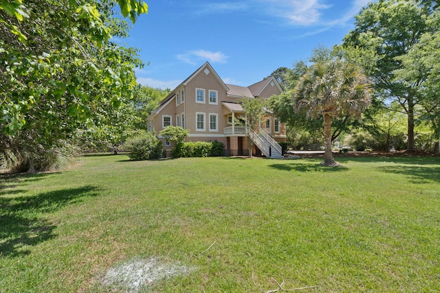 view of front of property featuring stairway, a front lawn, and stucco siding