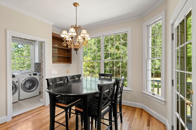 dining space featuring washer and clothes dryer, a chandelier, light wood-style floors, ornamental molding, and baseboards