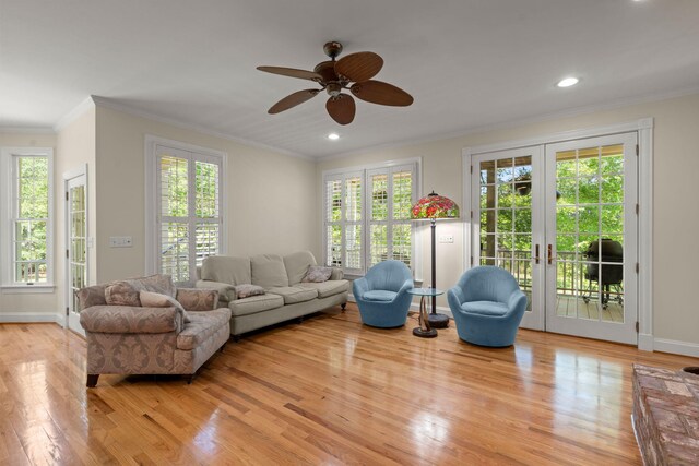 living area with wood finished floors, ceiling fan, ornamental molding, french doors, and baseboards