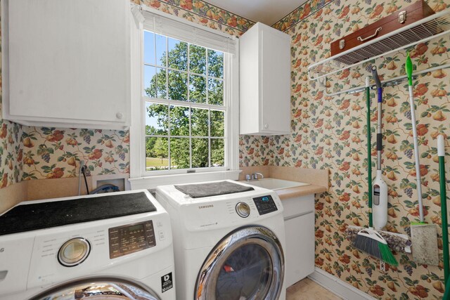 clothes washing area featuring independent washer and dryer, wallpapered walls, cabinet space, plenty of natural light, and baseboards
