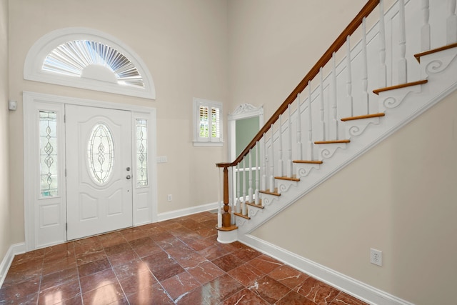 foyer entrance with baseboards, stairway, and a high ceiling