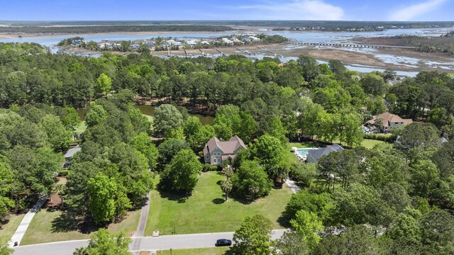 aerial view of property and surrounding area featuring a nearby body of water and a forest