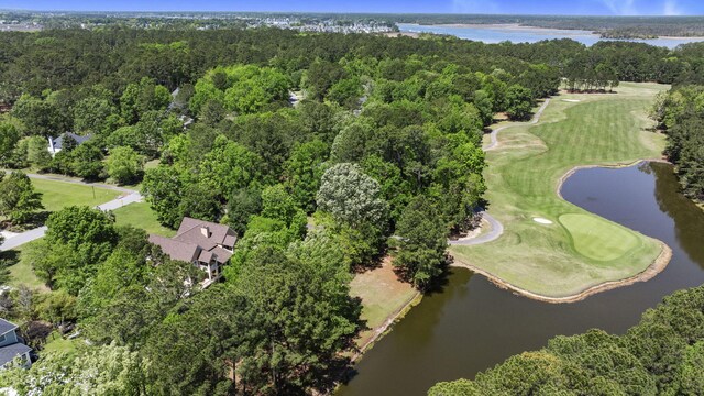 view of property location with a large body of water, a golf course, and a forest