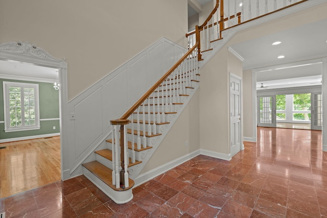 stairs with crown molding, healthy amount of natural light, a high ceiling, and baseboards