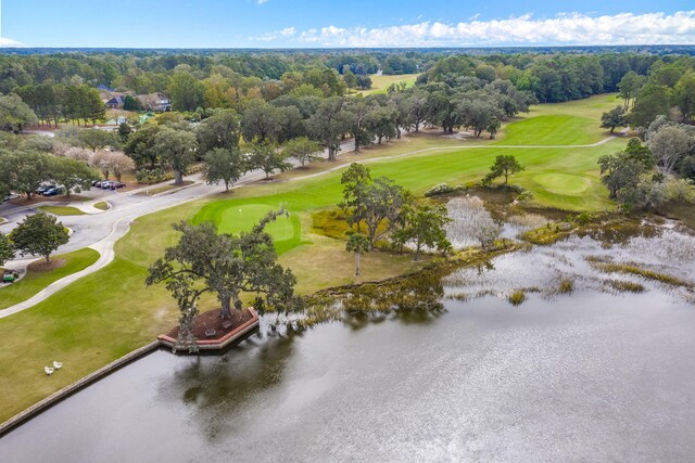 bird's eye view of a golf course, a large body of water, and a tree filled landscape