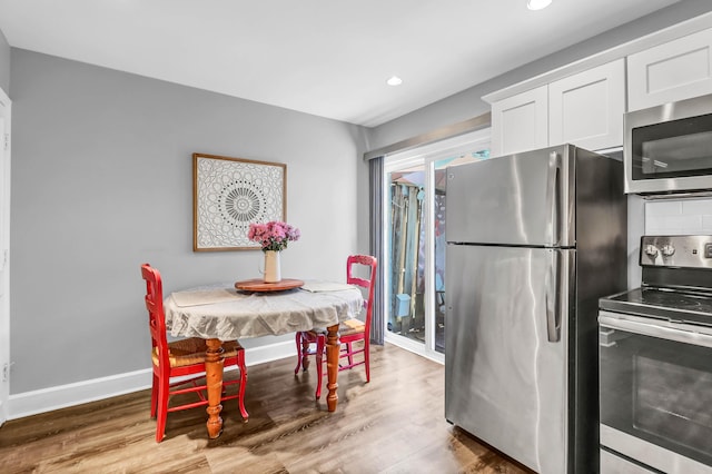 kitchen featuring appliances with stainless steel finishes, white cabinetry, baseboards, and wood finished floors