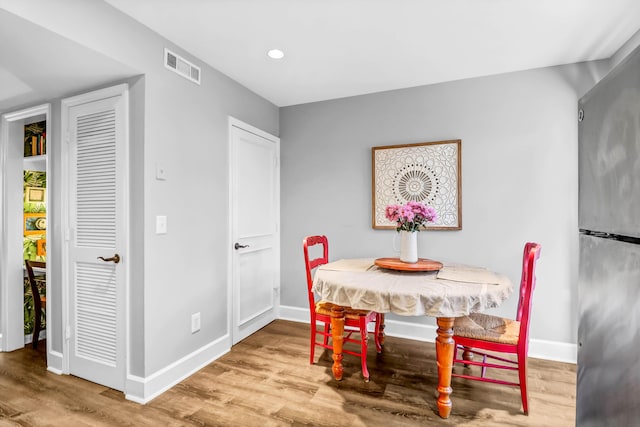 dining room featuring baseboards, visible vents, wood finished floors, and recessed lighting