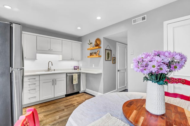 kitchen with appliances with stainless steel finishes, light countertops, visible vents, and a sink