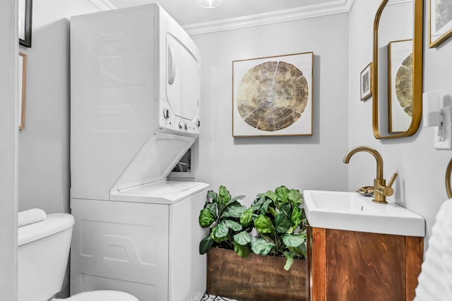 bathroom with stacked washer and dryer, crown molding, vanity, and toilet