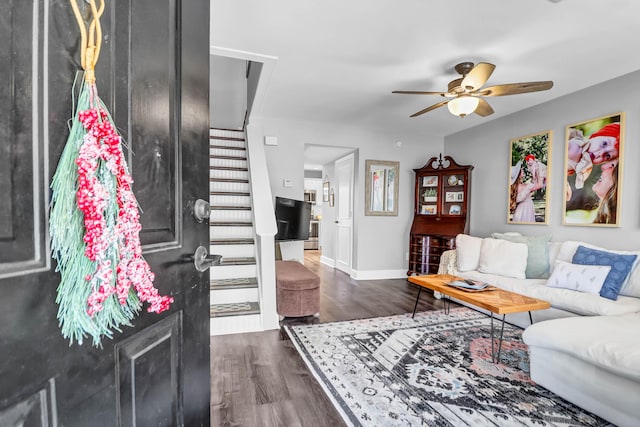 living room featuring dark wood-style floors, baseboards, stairway, and a ceiling fan