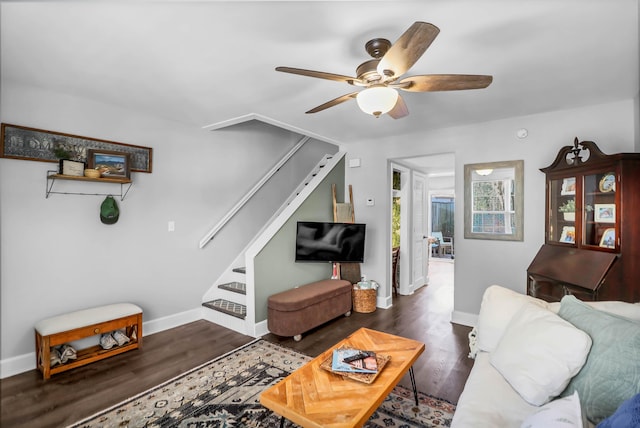 living room with ceiling fan, stairs, baseboards, and wood finished floors