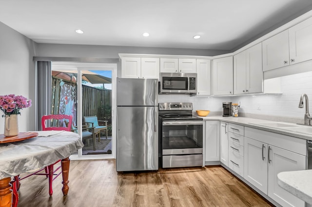 kitchen featuring light countertops, appliances with stainless steel finishes, a sink, and light wood-style floors