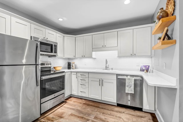 kitchen with decorative backsplash, appliances with stainless steel finishes, light countertops, open shelves, and a sink