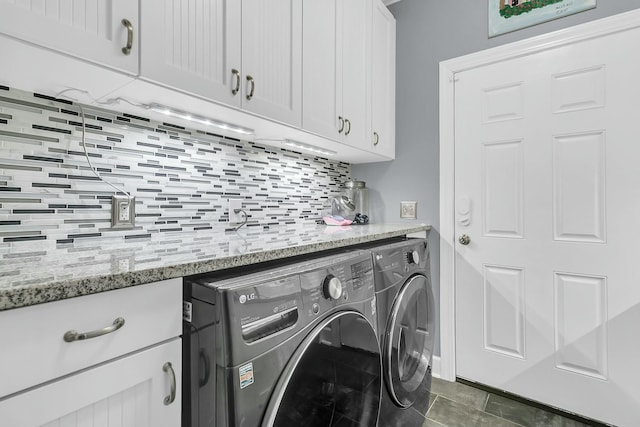 laundry room featuring washing machine and dryer, dark tile patterned flooring, and cabinets