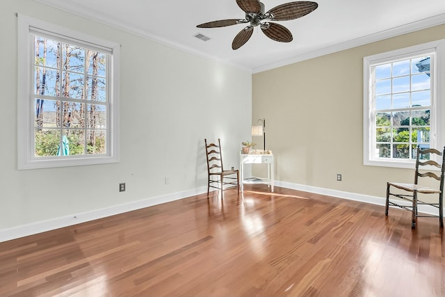 living area featuring a healthy amount of sunlight, ceiling fan, hardwood / wood-style floors, and crown molding