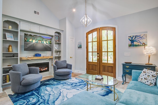 16 Oakwood Ln, Edisto Island, SC 29438 - living area featuring french doors, light wood finished floors, a chandelier, a glass covered fireplace, and high vaulted ceiling