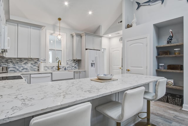 16 Oakwood Ln, Edisto Island, SC 29438 - kitchen featuring white appliances, a kitchen bar, tasteful backsplash, a peninsula, and high vaulted ceiling