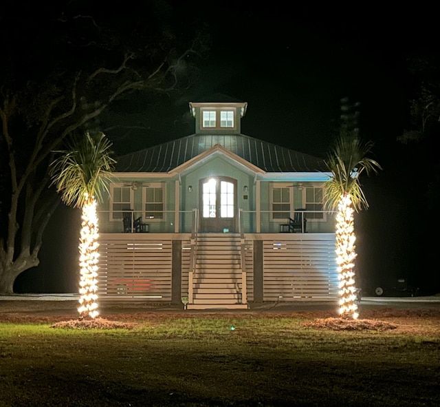 16 Oakwood Ln, Edisto Island, SC 29438 - back of house at night featuring a metal roof and covered porch