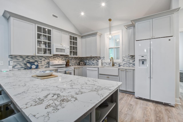 16 Oakwood Ln, Edisto Island, SC 29438 - kitchen with white appliances, lofted ceiling, a peninsula, backsplash, and glass insert cabinets