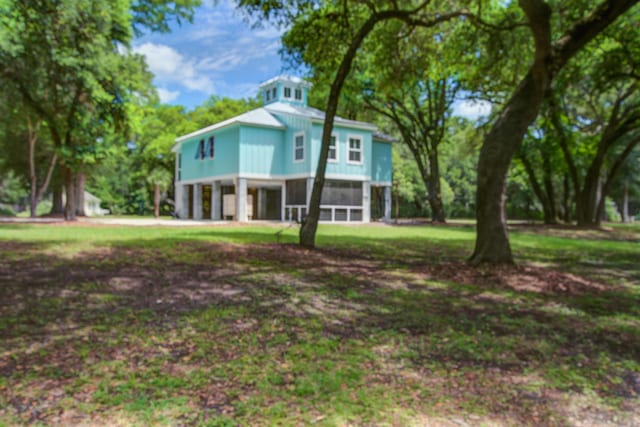16 Oakwood Ln, Edisto Island, SC 29438 - raised beach house with an attached garage, a front lawn, and a sunroom