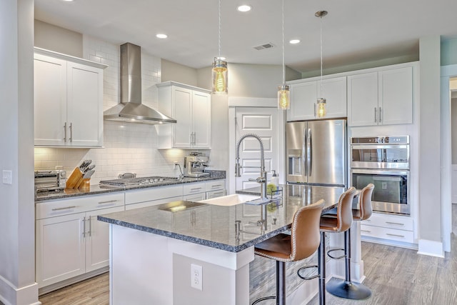 2336 Brinkley Rd, Johns Island, SC 29455 - kitchen featuring wall chimney range hood, stainless steel appliances, a sink, a center island with sink, and light wood-style flooring