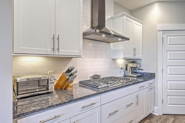 2336 Brinkley Rd, Johns Island, SC 29455 - kitchen featuring wall chimney exhaust hood, stainless steel gas cooktop, white cabinetry, dark stone countertops, and tasteful backsplash