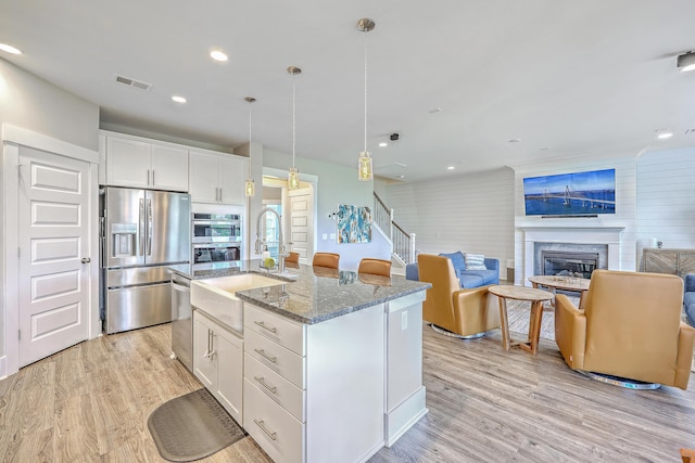 2336 Brinkley Rd, Johns Island, SC 29455 - kitchen with stainless steel appliances, dark stone counters, a sink, light wood finished floors, and recessed lighting