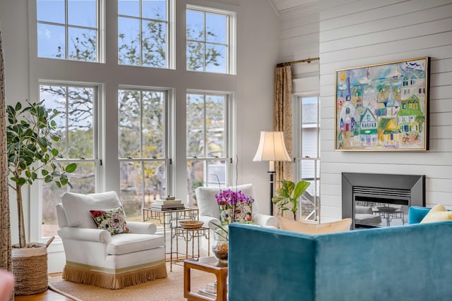 living room with a healthy amount of sunlight, a high ceiling, and wood walls