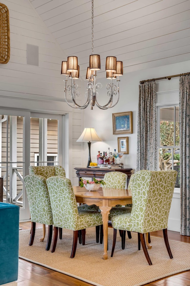 dining room with hardwood / wood-style flooring, high vaulted ceiling, and a chandelier