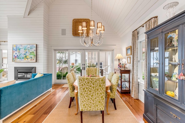 dining area with french doors, high vaulted ceiling, an inviting chandelier, and light wood-type flooring