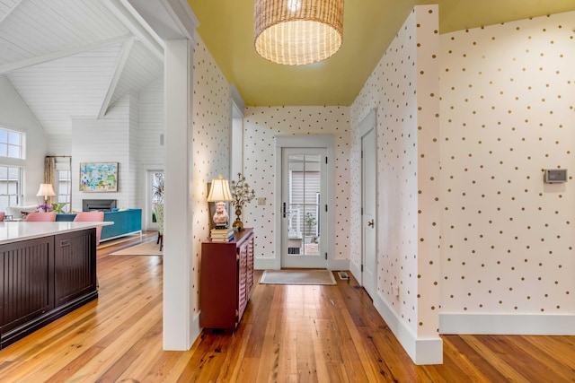 hallway featuring vaulted ceiling, light hardwood / wood-style floors, and a notable chandelier