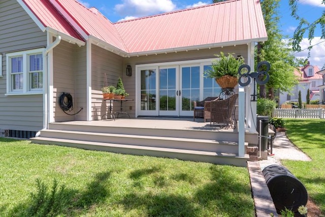 rear view of property with a wooden deck, a lawn, and french doors