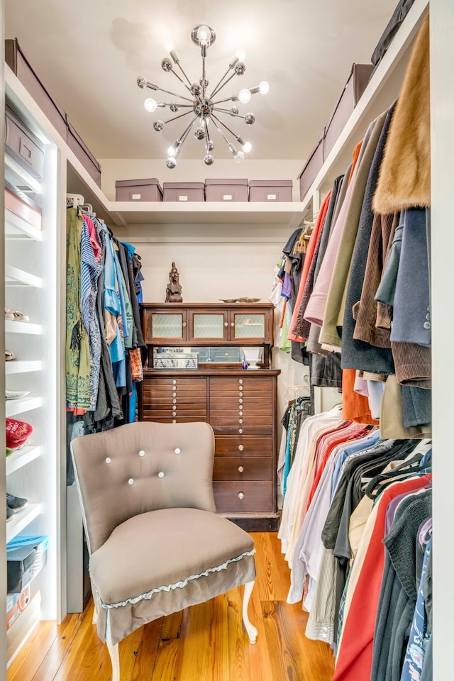 spacious closet with a chandelier and light hardwood / wood-style floors