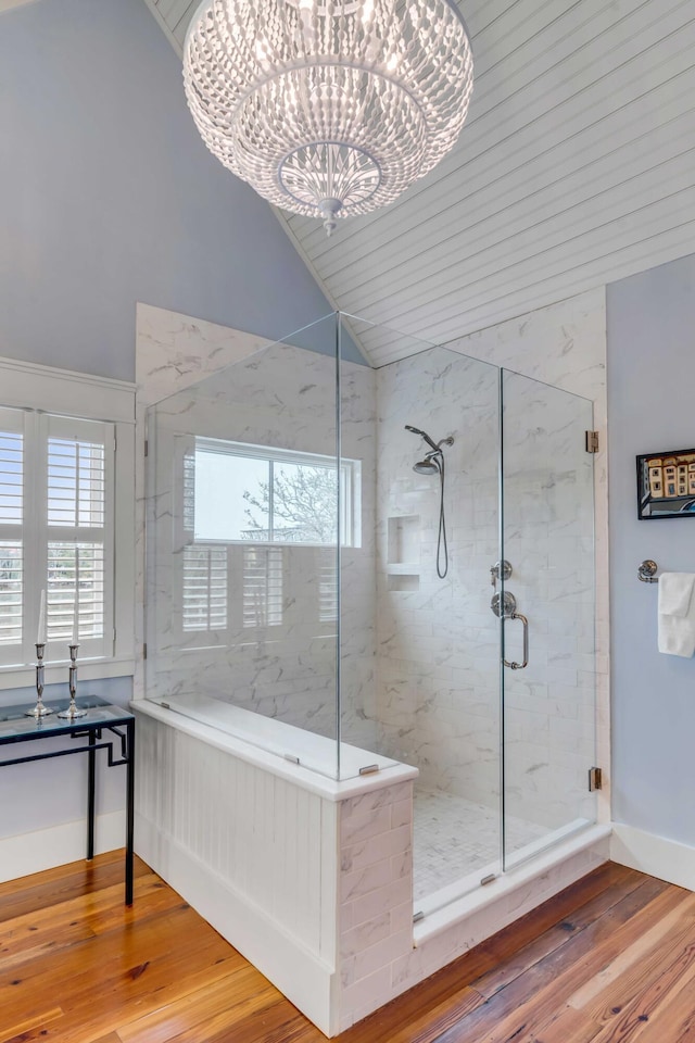 bathroom with a shower with door, vaulted ceiling, hardwood / wood-style floors, and a notable chandelier