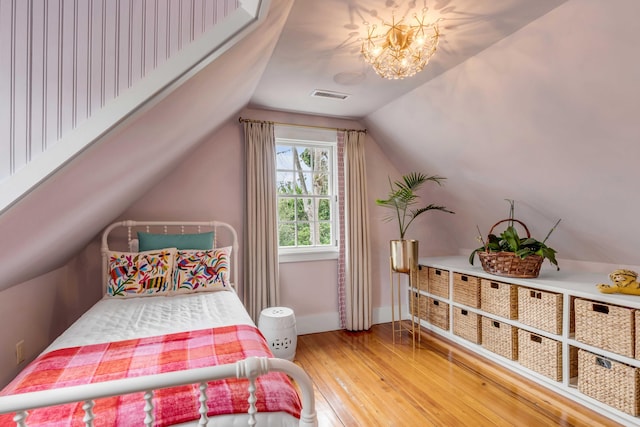 bedroom featuring hardwood / wood-style flooring, lofted ceiling, and an inviting chandelier