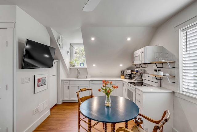 kitchen with sink, white appliances, white cabinets, and light wood-type flooring