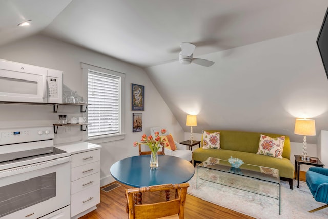 living room with ceiling fan, vaulted ceiling, and light hardwood / wood-style flooring