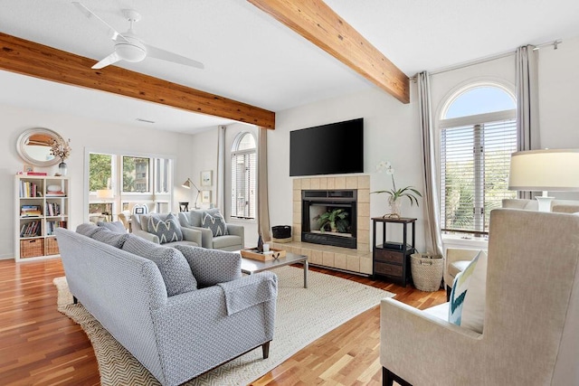 living room featuring ceiling fan, light wood-type flooring, plenty of natural light, and a tiled fireplace